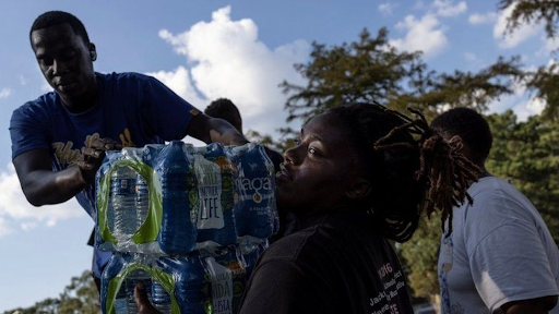 Volunteers handing water bottles out for Jackson residents (BBC News) 
