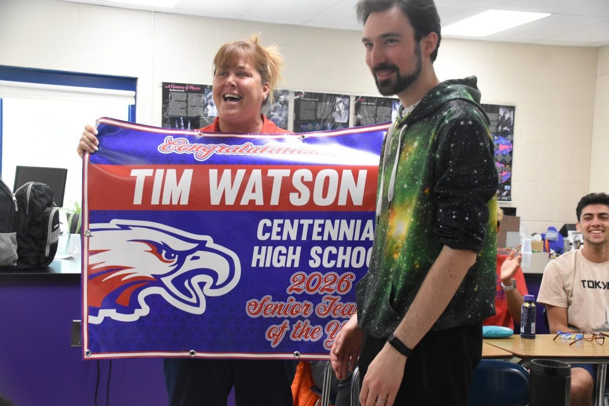 Mr. Watson is presented with a banner signifying his award as 2025-26 teacher of the year.